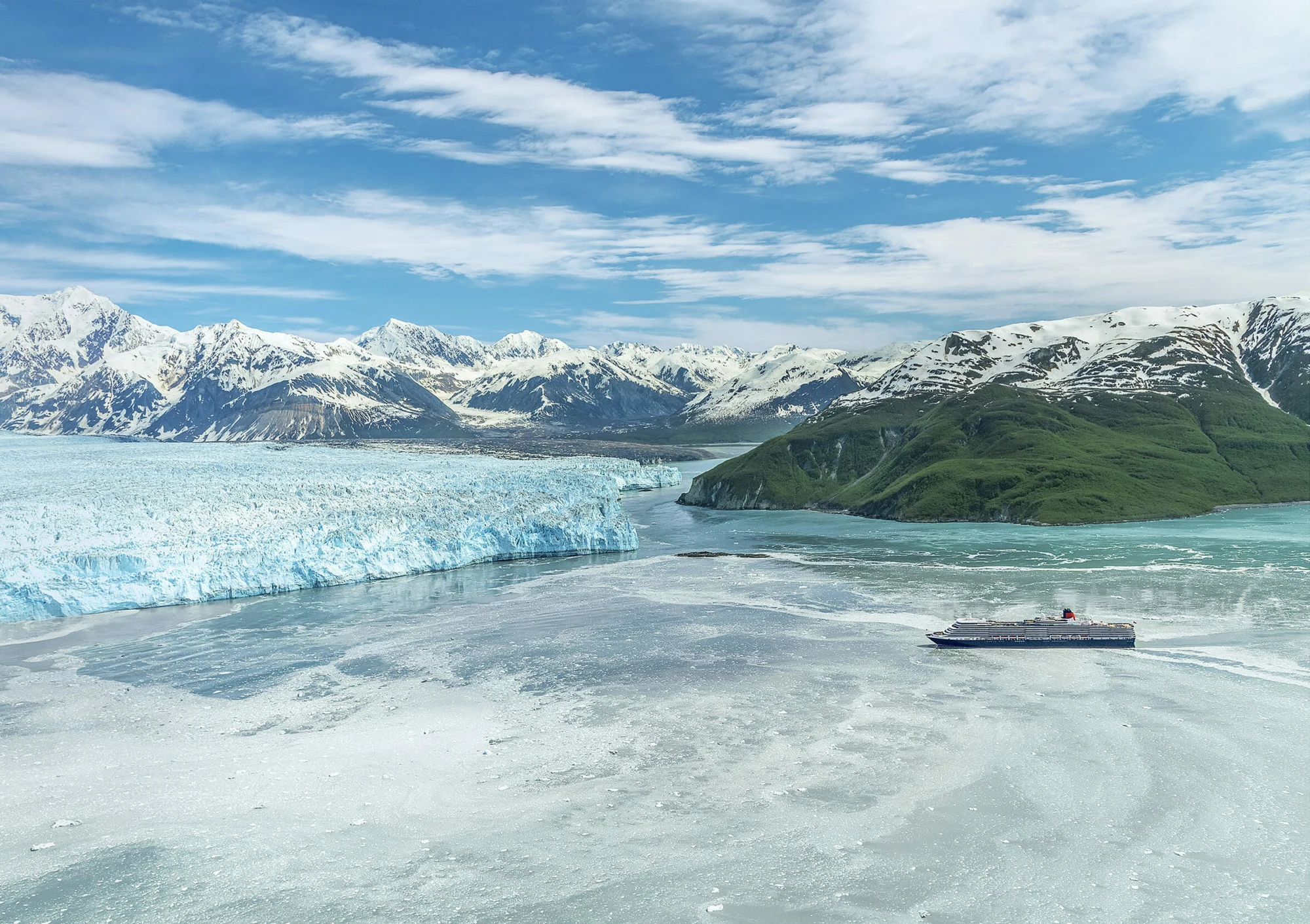 Cruise ship sailing beside the immense ice wall of Hubbard Glacier in Alaska