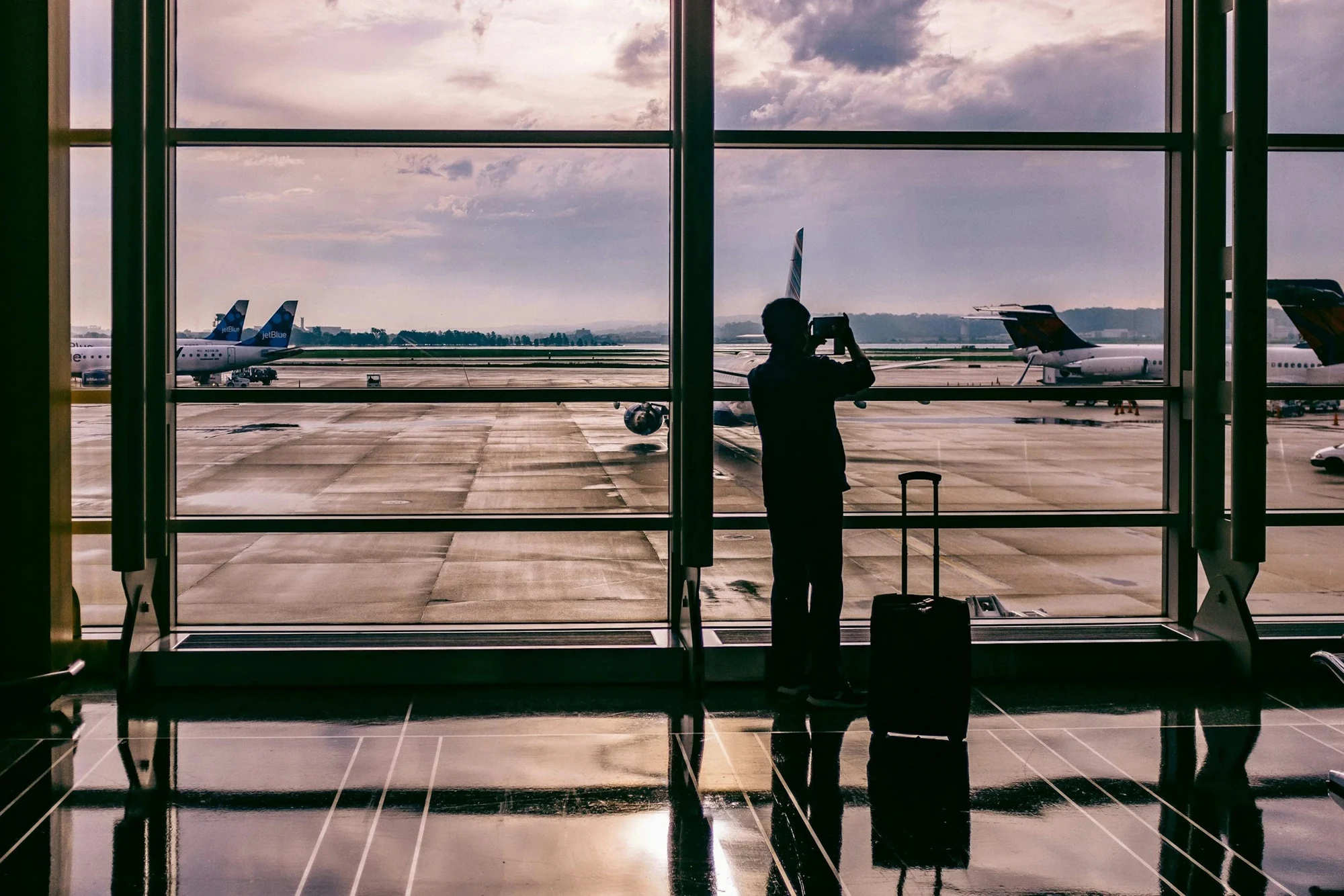 Traveler looking through an airport window at parked aircraft