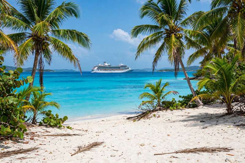 Turquoise Caribbean water and white sand beach with a luxury ship offshore